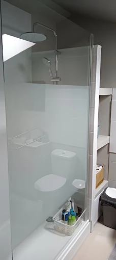 Douche à paroi vitrée avec colonne de douche, étagères intégrées à côté