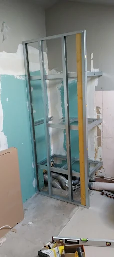 Ossature métallique montée contre un mur, tuyaux au pied