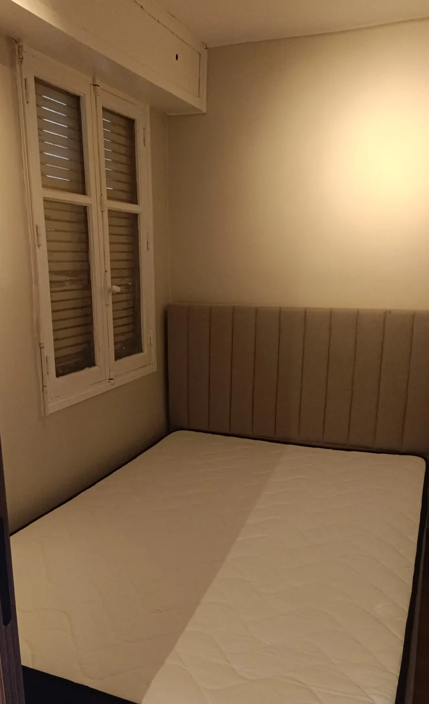 Chambre terminée : murs et plafond peints, lit à tête capitonnée contre le mur du fond