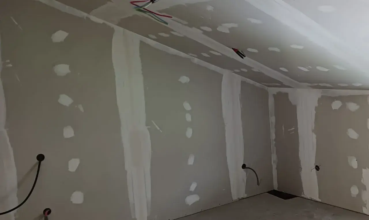 Pièce sous pente habillée de plaques de plâtre : joints et têtes de vis enduits, fils électriques en attente au plafond