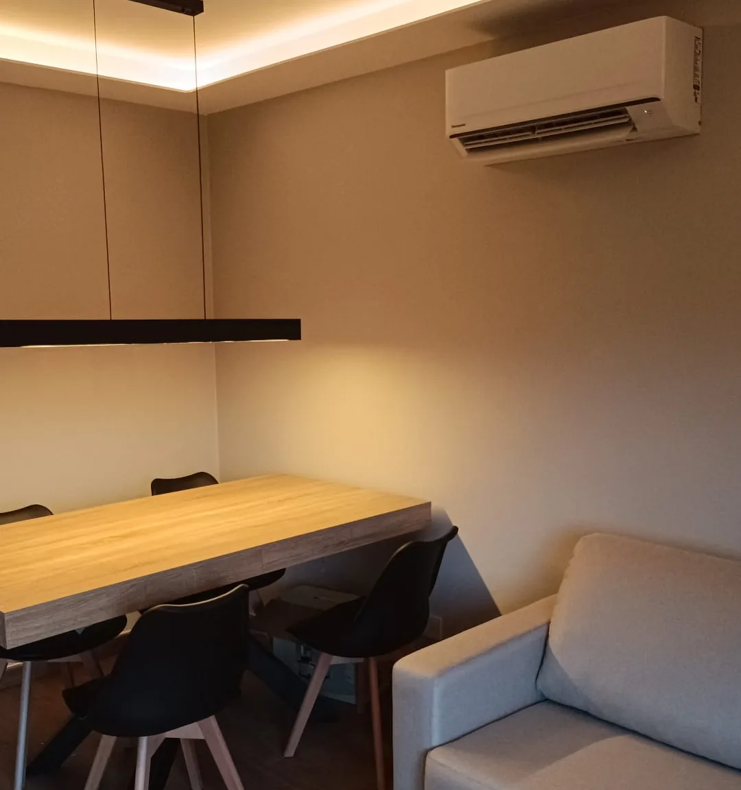 Coin repas terminé : murs peints, faux plafond à bandeau lumineux, table et banquette